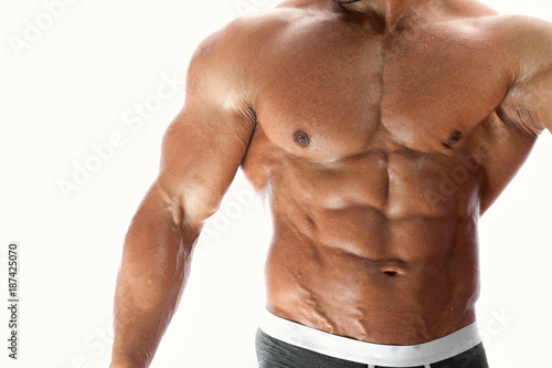 Studio shot of sexy muscular fitness model demonstrating perfect abdominal muscles. Young handsome man posing over white background. Place for text, high resolution