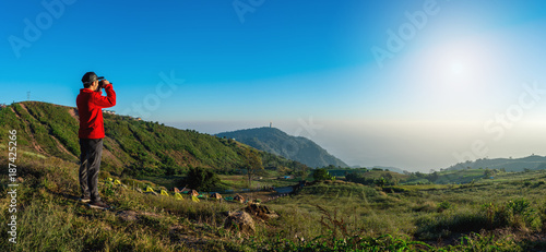 Canvas Print traveler looking in binoculars enjoying view above clouds
