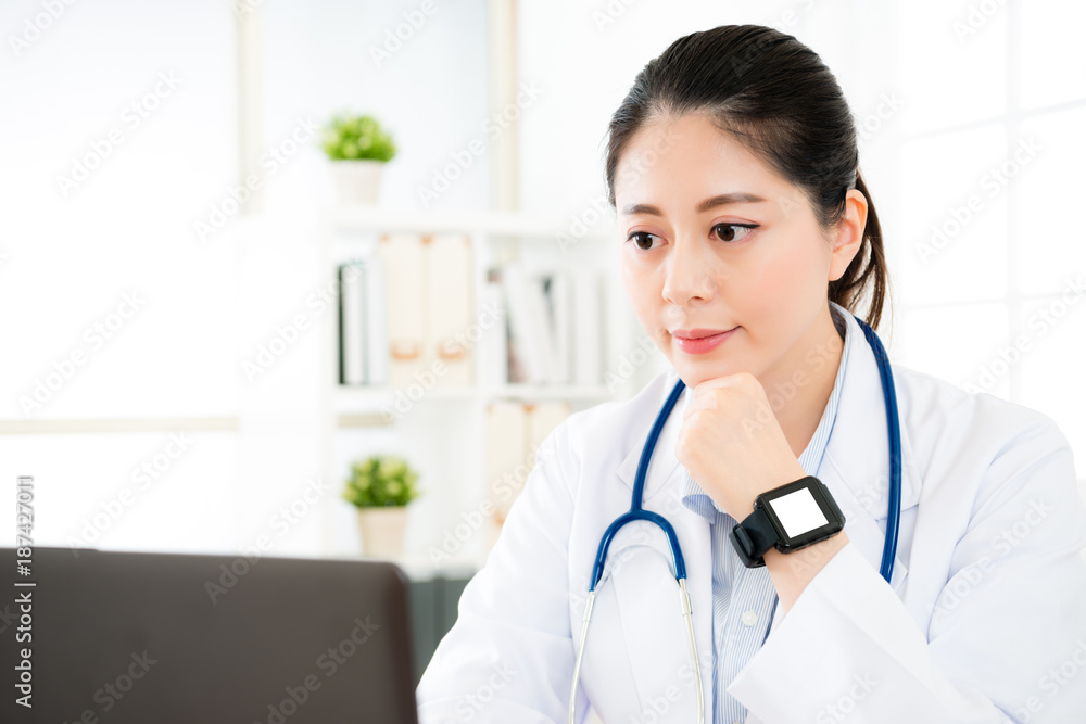 confident female doctor looking at mobile computer confident female doctor looking at mobile computer