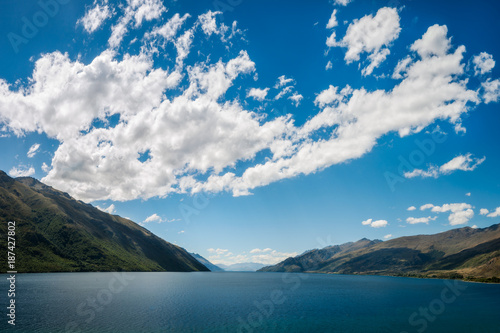 Simple Perspective background, only water, hills and puffy clouds in the sky, at Lake Wakatipu in the Southern Island of New Zealand. © Daniela Photography