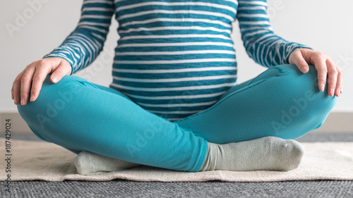 Pregnant woman practicing yoga exercise at home.