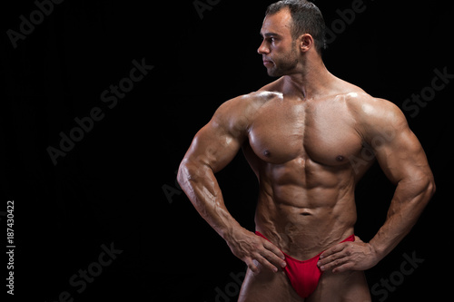 Handsome muscular bodybuilder with perfect flexed muscles posing against black background. Studio shot of high level middle aged fitness model. Place for text, high resolution
