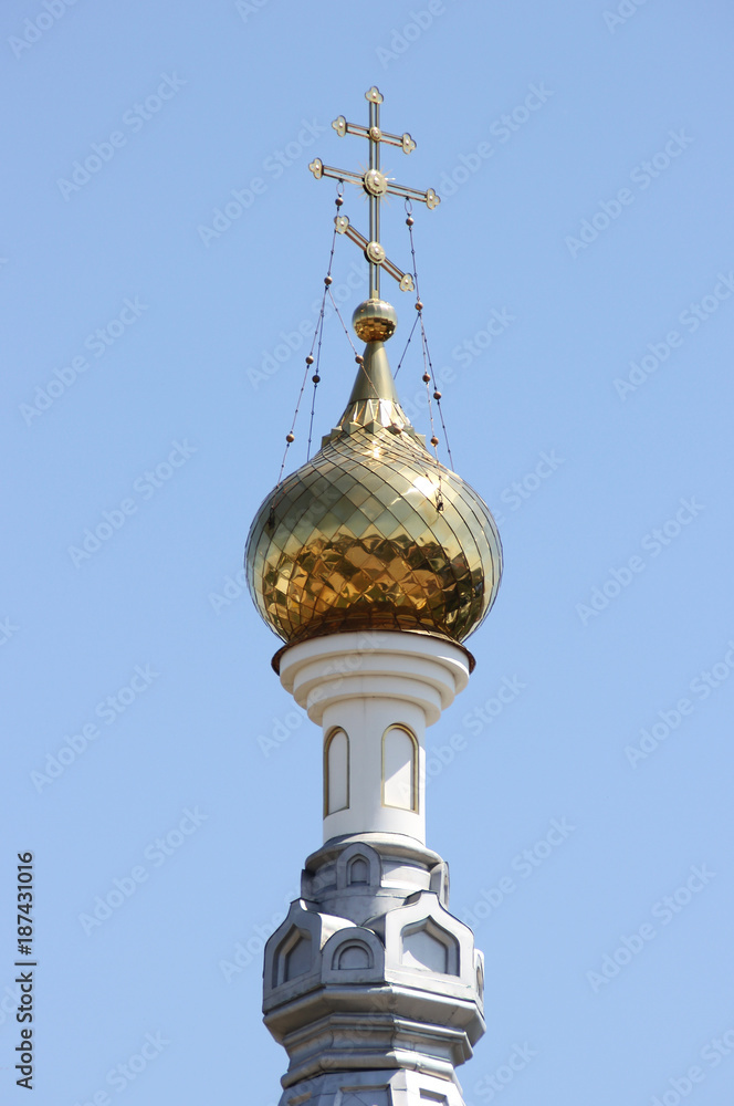 The golden dome of the church with a cross. Gold dome on a background of blue sky. A beautiful architectural structure. The golden dome of the church with a cross. Gold dome on a background of blue sky. A beautiful architectural structure.