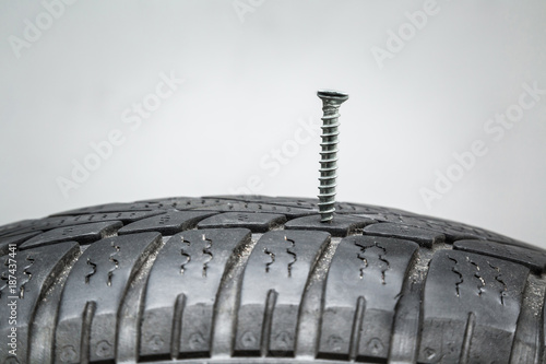 Screw in the black tire. Damaged tire problems and solutions concept. photo