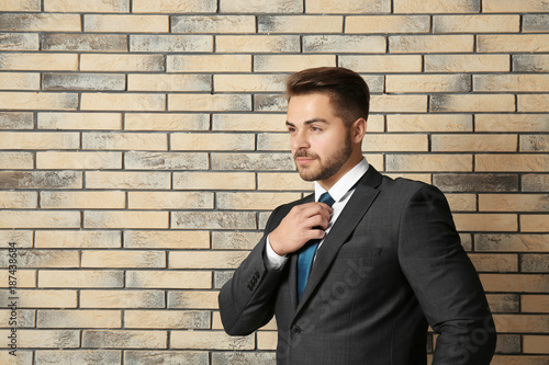 Handsome man in formal suit against brick wall