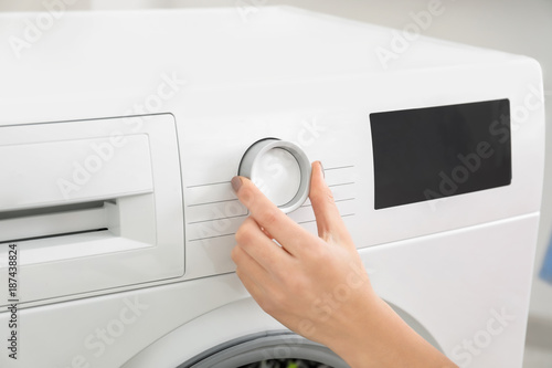 Woman choosing washing machine program for laundry, closeup