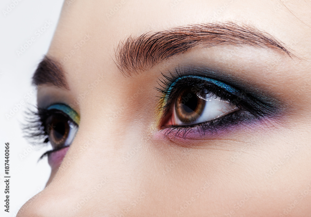 Naklejka premium Closeup macro shot of human female eye. Girl with perfect skin and lilac - blue - yellow eyes shadows
