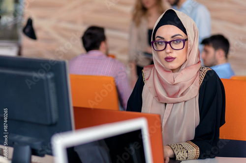 Bild auf Leinwand Attractive Muslim young woman working in office on computer