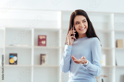 Emotional conversation. Appealing attractive young woman speaking on the phone while gesturing and gazing aside