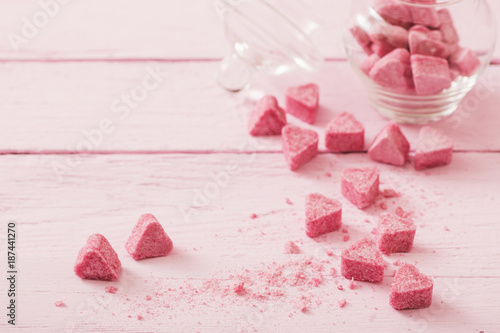 Granulated pink sugar in the shape of heart on a wooden background