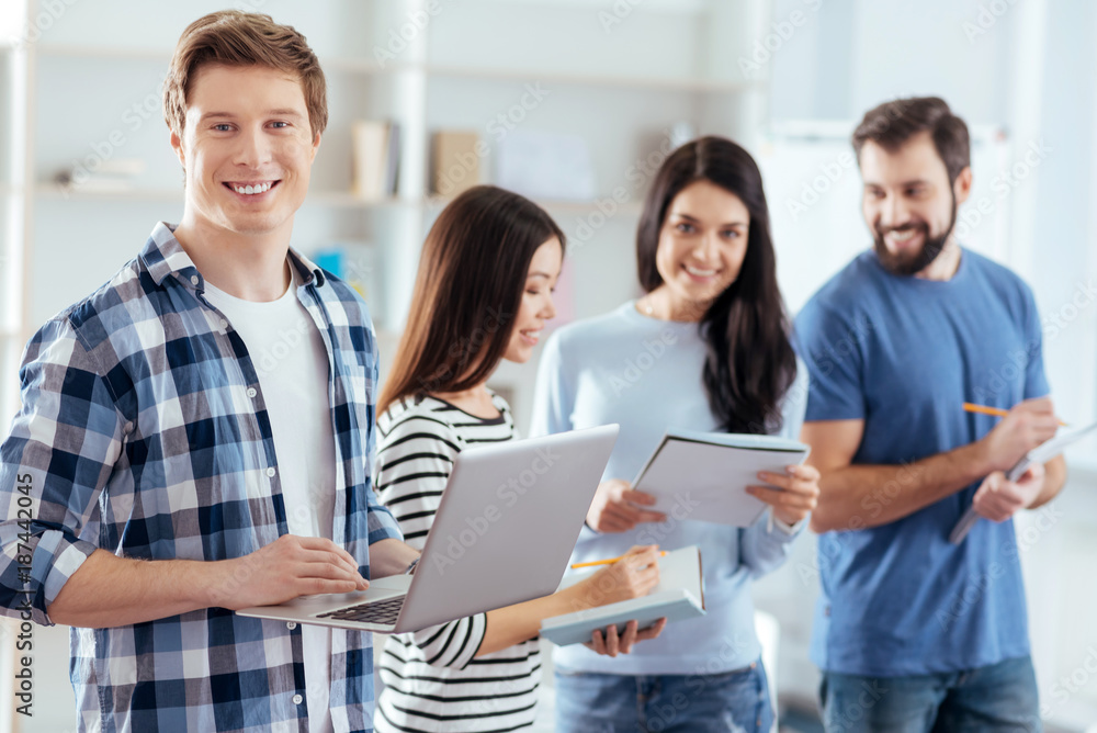 Obraz premium Task for everyone. Skillful pleasant four colleagues working while communicating and man compiling presentation