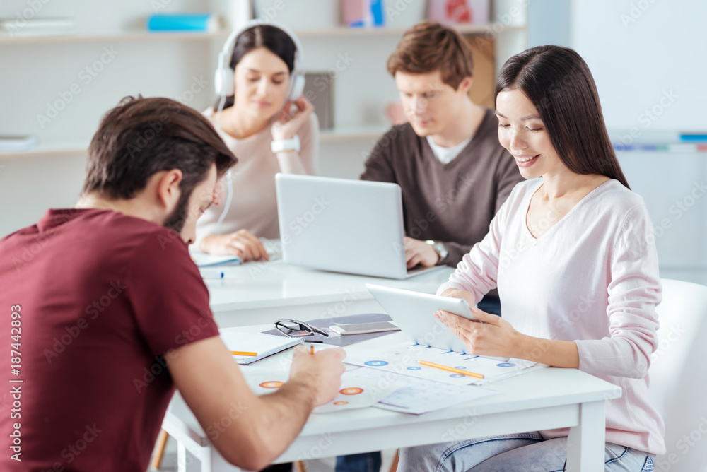 Work day. Thoughtful young four colleagues working while sitting at the table and looking down