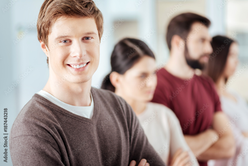 Professional realization. Glad merry appealing man staring at the camera and grinning while posing on the blurred background Professional realization. Glad merry appealing man staring at the camera and grinning while posing on the blurred background