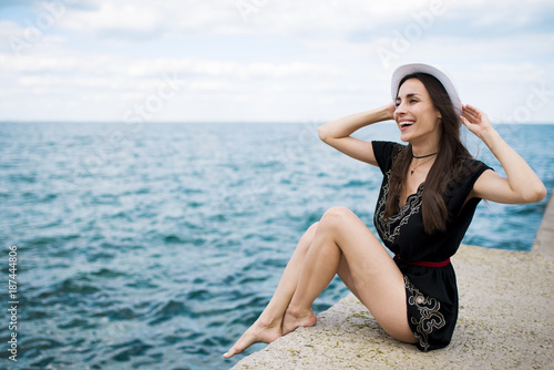 Modern beautiful young woman in white hat on the sea beach. Summer rest