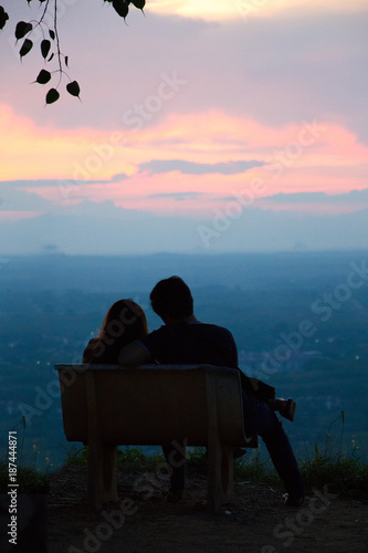 silhouette lovers sitting on chair looking to top view of town