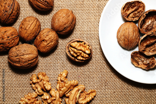 Walnuts, peel and white plate on the background of sacking.