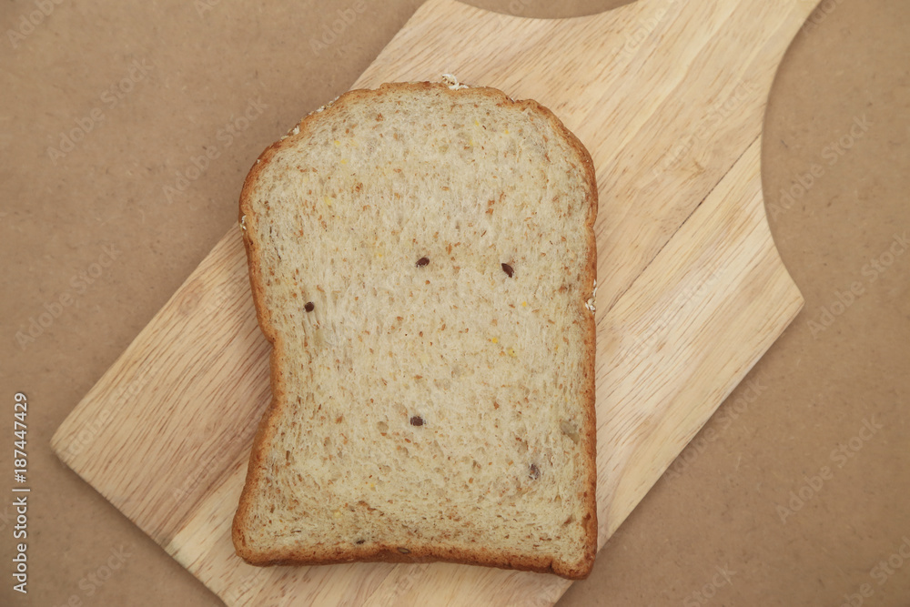 Whole grain bread on wood plate and brown texture background.