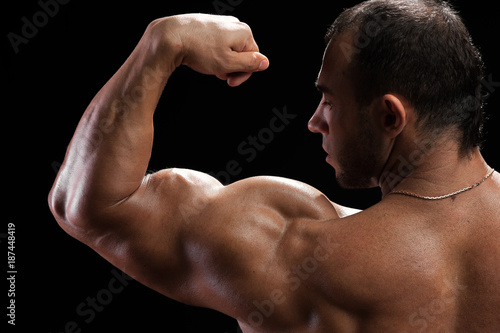 Closeup of handsome muscular bodybuilder showing biceps muscles