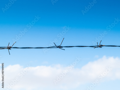 barbed wire with blue sky background with some clouds