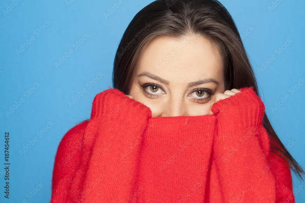 beautiful ashamed woman in a red sweater on a blue background beautiful ashamed woman in a red sweater on a blue background