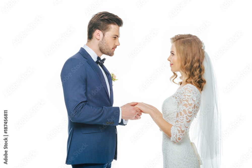 side view of beautiful wedding couple holding hands and looking at each other isolated on white side view of beautiful wedding couple holding hands and looking at each other isolated on white