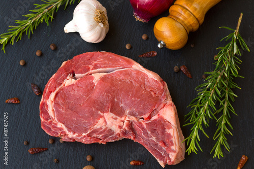 Juicy raw meat, beef entrecote on black background, top view photo