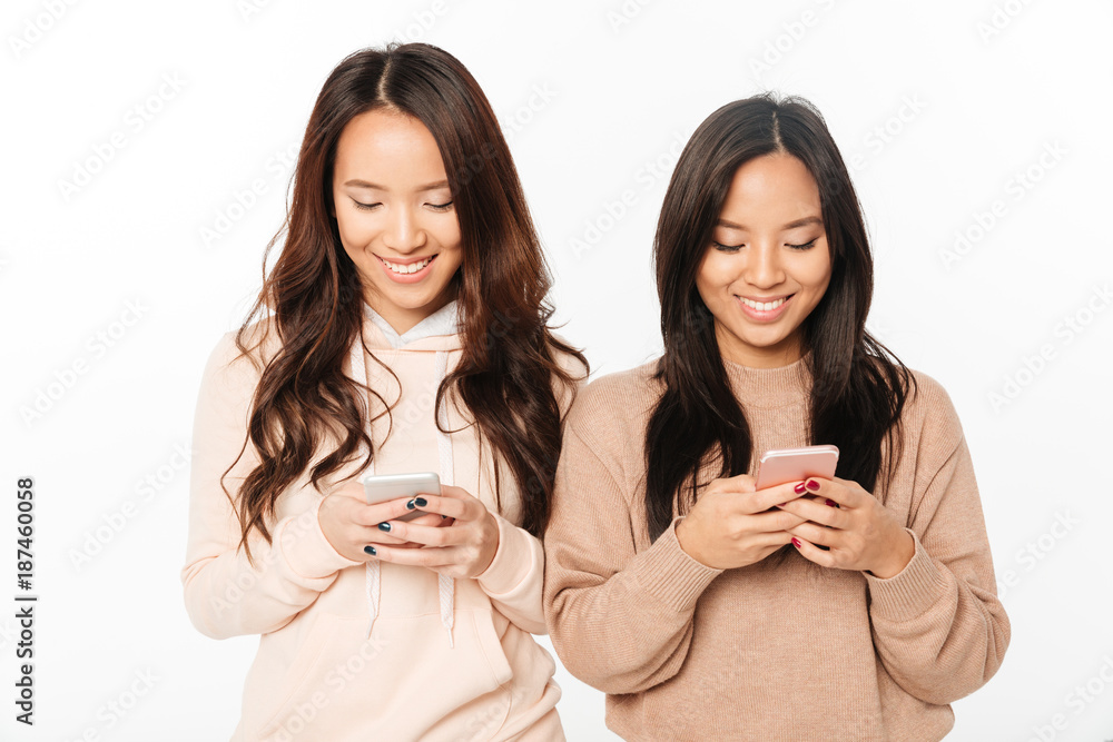 Asian pretty happy ladies sisters chatting by mobile phones. Asian pretty happy ladies sisters chatting by mobile phones.