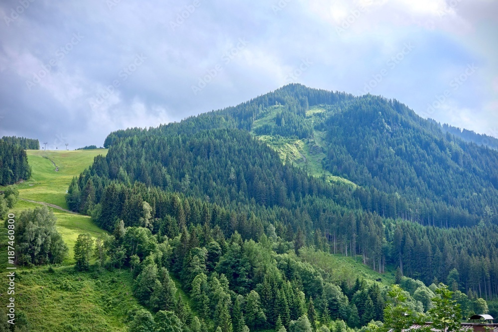 lush green alpine peak under a blue cloudy sky in Saalbach, Austria