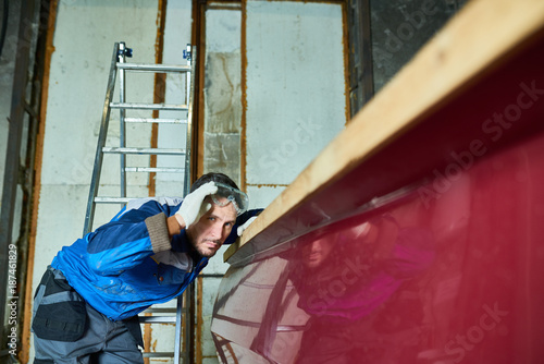 Canvas Print Portrait of handsome worker checking paint coating while repairing boat in yacht