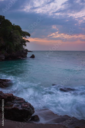 View of coastline on Nosy Komba Island lined with palm trees and boats floating in the sea at sunset, Nosy Komba, Madagascar photo