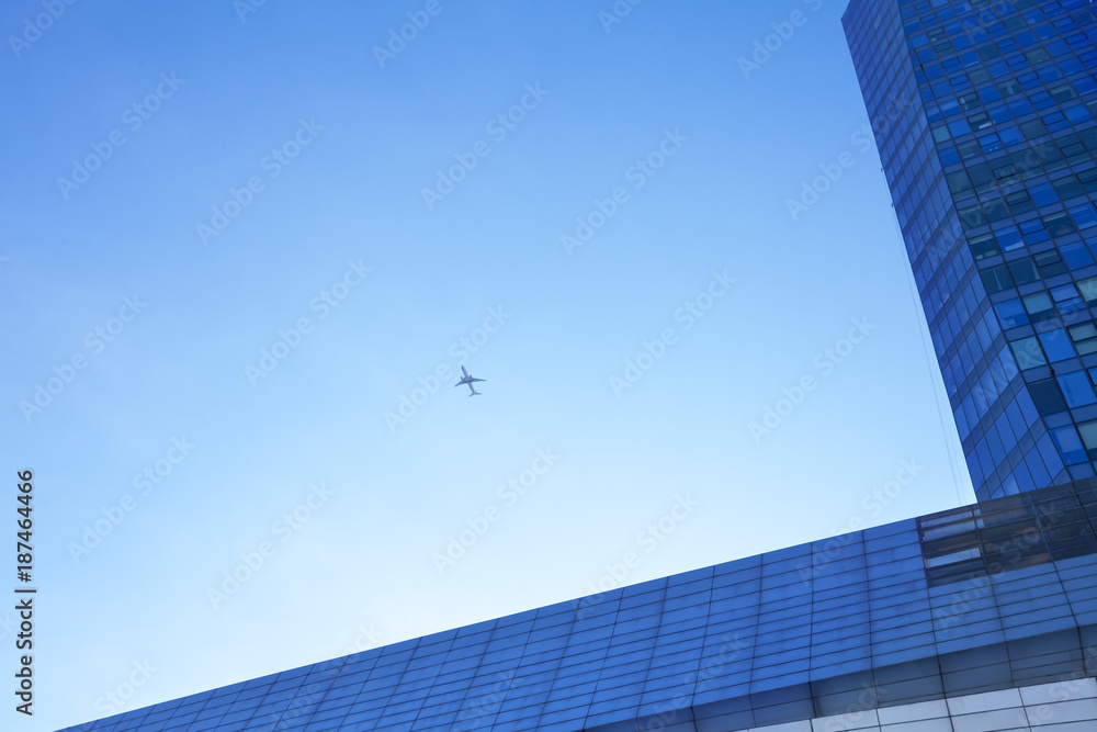 Airplane flying above glass office buildings and futuristic design Airplane flying above glass office buildings and futuristic design