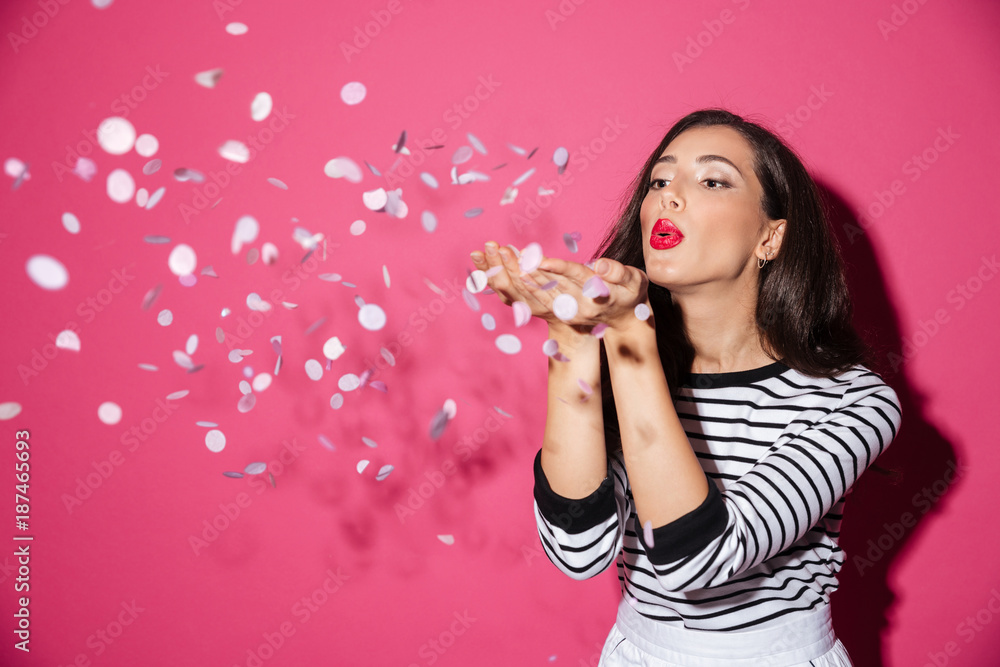 Portrait of a pretty woman blowing confetti - obrazy, fototapety, plakaty 