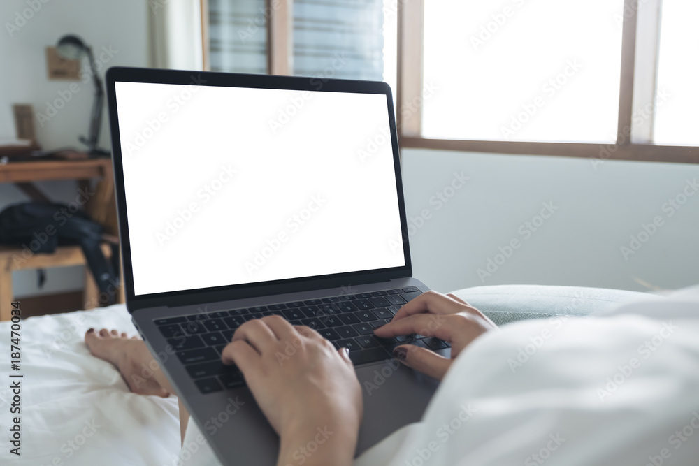 Mockup image of a woman lying on a bed , using and typing on laptop with blank white desktop screen keyboard Mockup image of a woman lying on a bed , using and typing on laptop with blank white desktop screen keyboard