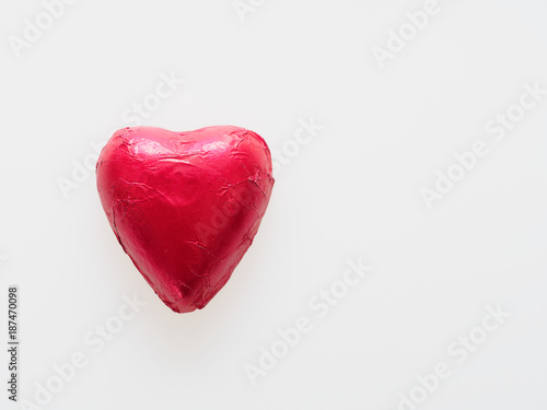Heart shape chocolate wrapped in red foil isolated over white background