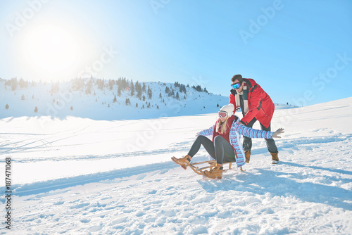 Young Couple Sledding And Enjoying On Sunny Winter Day