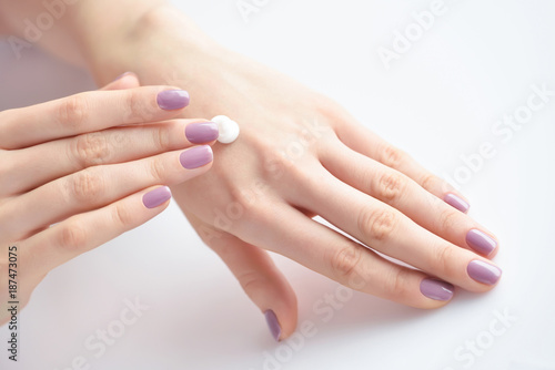 Women s hands with pink manicure applying cream. The concept of skin care.