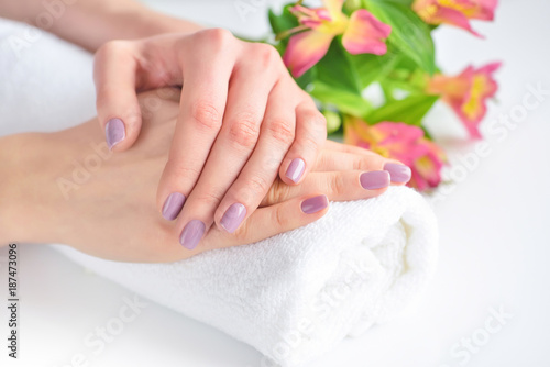 Hands of a woman with pink manicure are on a towel