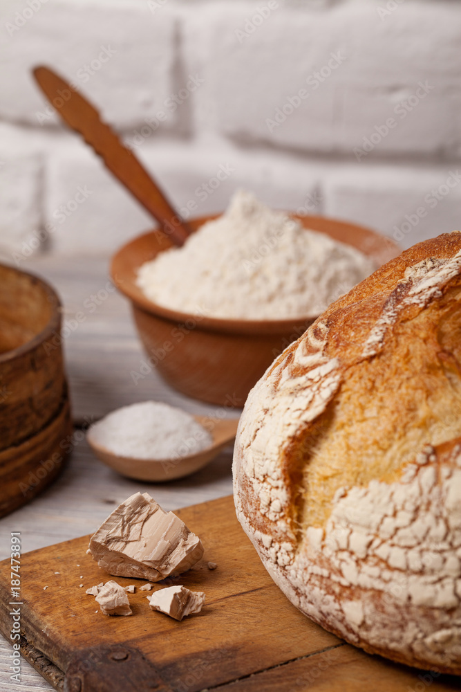Fototapeta premium Homemade bread on old cutting board with a pile of fresh yeast