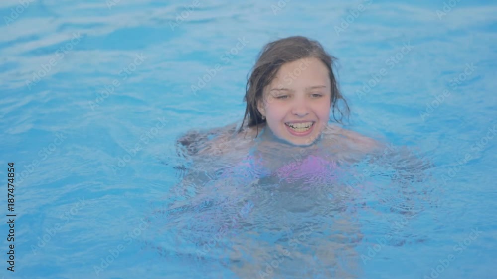 Young girl swims in swimming pool. Teen girl enjoys summer vacation on a sunny day in water of outdoor pool. Young girl swims in swimming pool. Teen girl enjoys summer vacation on a sunny day in water of outdoor pool.