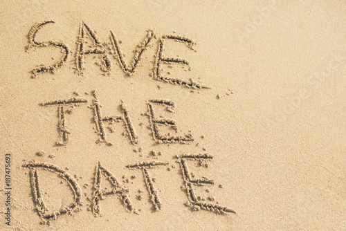 Save the Date text written on the sand