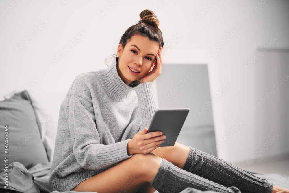 Woman using tablet while sitting on the bed in the morning. Woman using tablet while sitting on the bed in the morning.