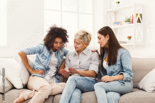 Three young female friends chatting at home