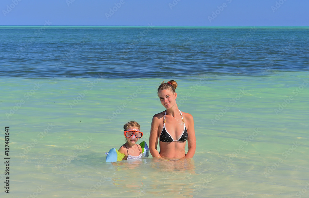 Summer vacation. Mother and cute daughter playing and swimming in blue ocean. Cuba. Caya Coco