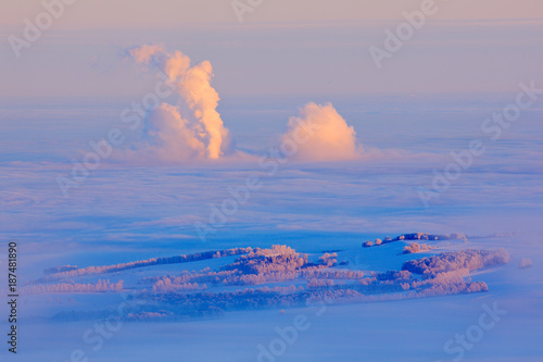 Blue winter landscape  smoke from factory  ice and rime. Pink morning light before sunrise. Winter twilight  cold nature in forest. Orlicke hory  Czech republic. Mountain landscape with trees