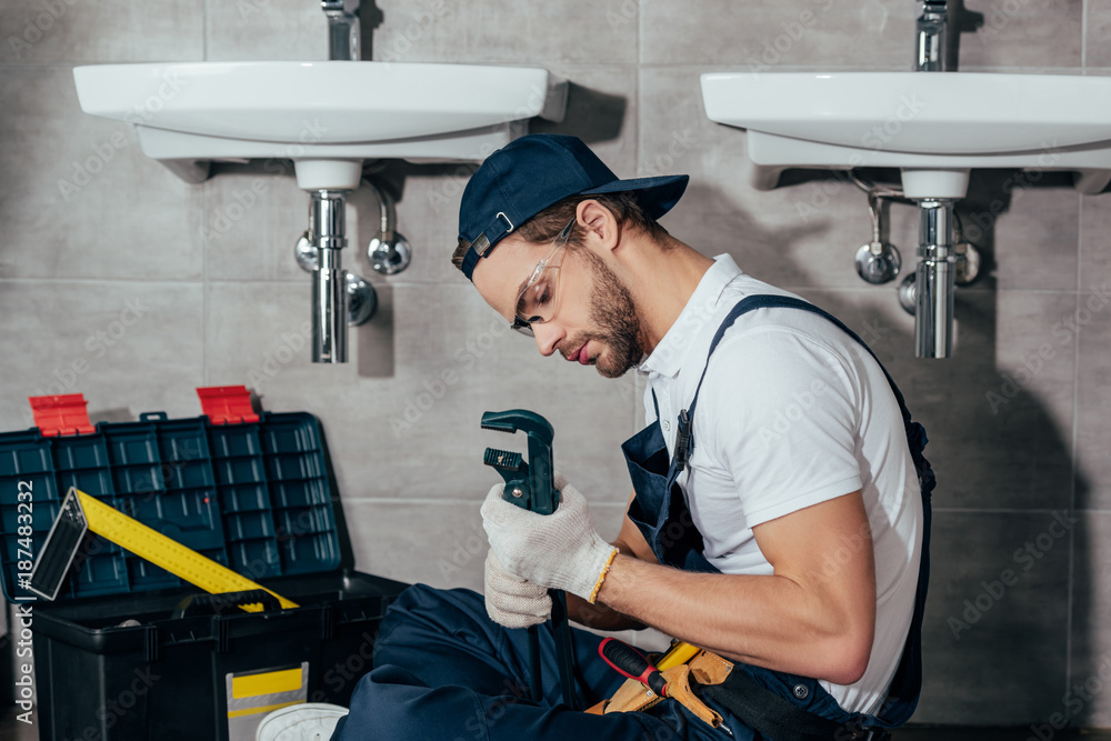 Fototapeta premium young professional plumber fixing sink in bathroom