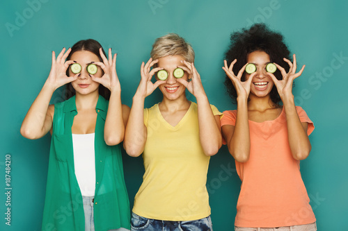 Three beautiful girls covering eyes with cucumber pieces photo