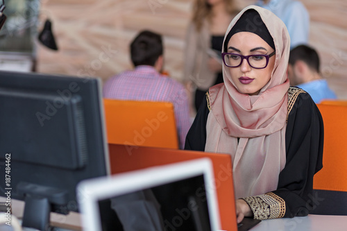 Bild auf Leinwand Attractive Muslim young woman working in office on computer
