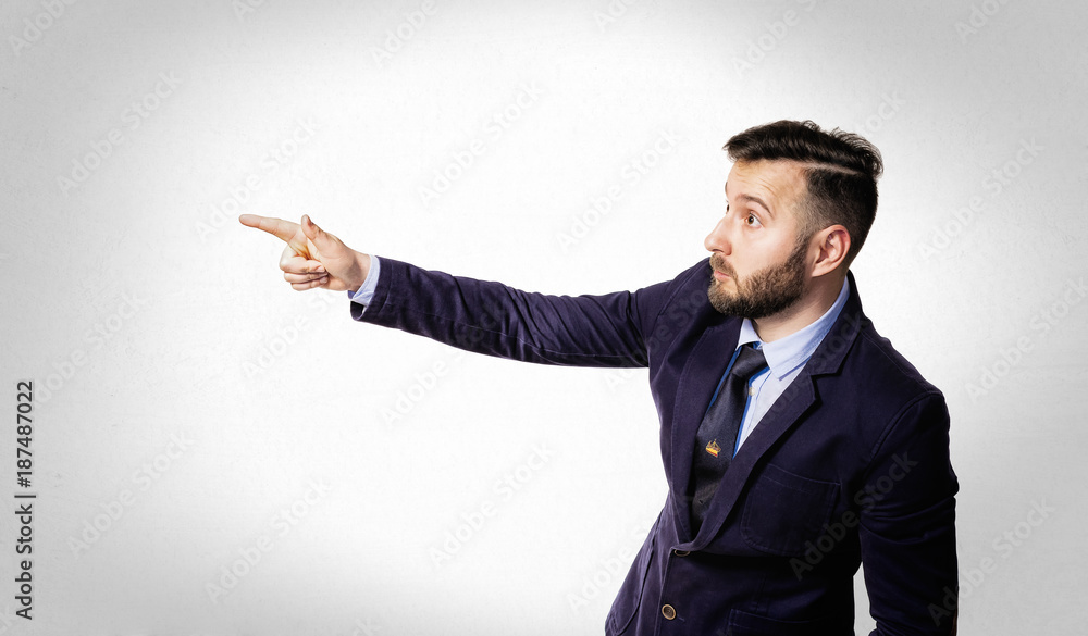 Portrait of a bearded man in a suit on a light background. He points emotionally with his finger. Portrait of a bearded man in a suit on a light background. He points emotionally with his finger.