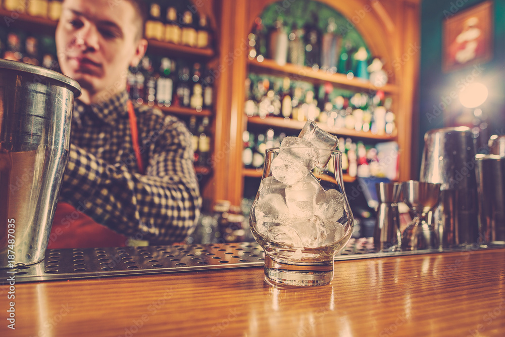 Barman making an alcoholic cocktail at the bar counter on the bar background