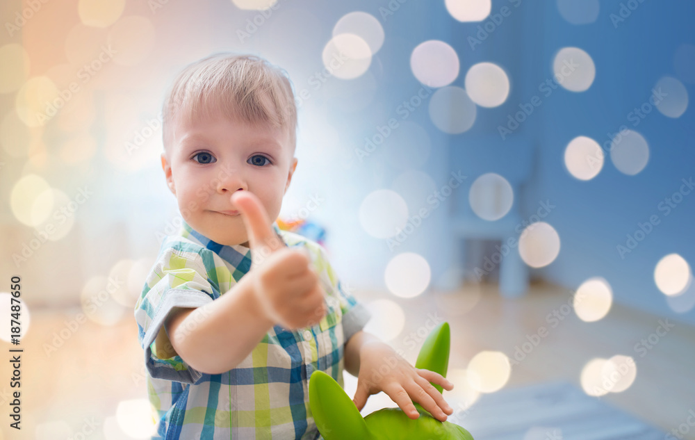happy baby boy playing with toy showing thumbs up happy baby boy playing with toy showing thumbs up
